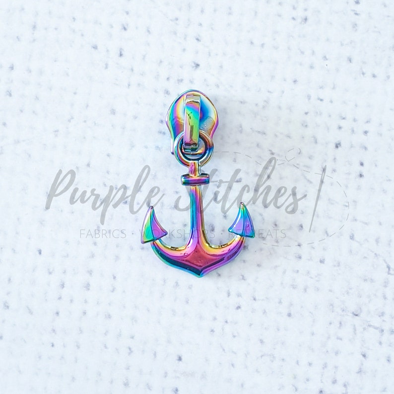 May include: A rainbow iridescent zipper pull with an anchor design. The anchor is a popular nautical theme.