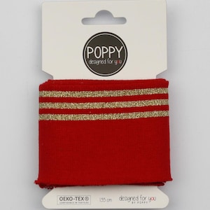 Könnte beinhalten: Rote Strickmanschette mit drei goldenen Streifen. Die Manschette ist 135 cm lang und trägt das Label "POPPY designed for you".