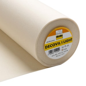 Könnte beinhalten: Eine Rolle beigen Decovil I Light Stoffes. Das Etikett gibt an, dass der Stoff 90 cm x 15 m groß ist und aus 42 % PES, 35 % CV und 23 % PA besteht. Der Stoff hat eine hellbeige Farbe.