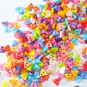 Peut inclure: Un grand assortiment de perles triangulaires en plastique de couleurs vives. Les perles sont dans différentes nuances de rose, bleu, vert, jaune, orange et blanc.