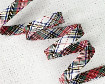 May include: Red, green, blue, and yellow plaid ribbon with a white background. The ribbon is folded and twisted.