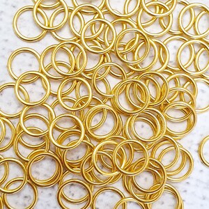 May include: A large pile of gold jump rings. The rings are all the same size and are arranged in a random pattern.