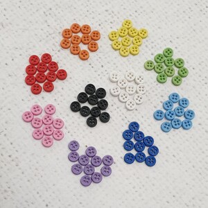 May include: Assortment of colourful buttons in various shapes and sizes. The buttons are made of plastic and have a smooth finish. The colours include red, orange, yellow, green, blue, black, and white.
