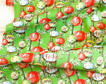 May include: Green fabric with a repeating pattern of red, white, and blue Christmas ornaments hanging from green pine branches.