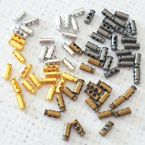 Puede incluir: Surtido de terminales de cordón de metal en acabados plateado, dorado y bronce. Los terminales de cordón se utilizan para hacer joyas, ropa y otras artesanías.