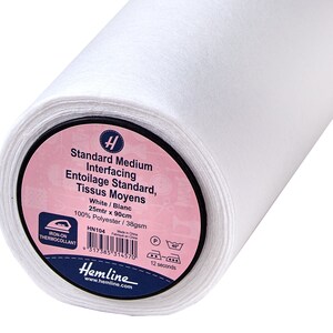 Puede incluir: Un rollo de entretela estándar media blanca. La etiqueta dice "Standard Medium Interfacing, Blanco, 25 m x 90 cm, 100% Poliéster". La marca "Hemline" es visible en la etiqueta. La tela es termoadhesiva.
