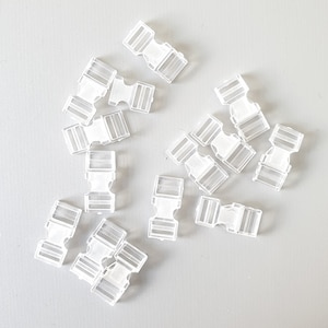 Puede incluir: Un grupo de 14 cierres de hebilla de plástico blanco. Las hebillas están diseñadas para ser utilizadas para correas, bolsos u otros proyectos.