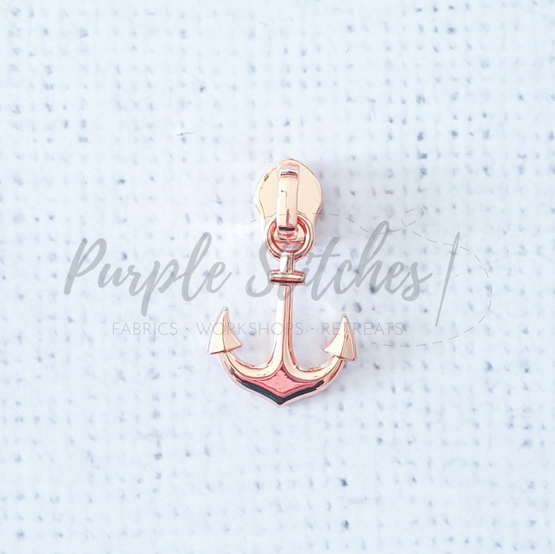 May include: Rose gold zipper pull with an anchor design.