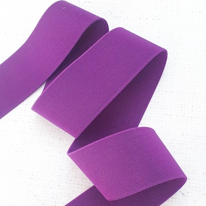 Pu&ograve; includere: Nastro elastico viola, piegato in tre parti, mostrando la trama e il colore del tessuto.