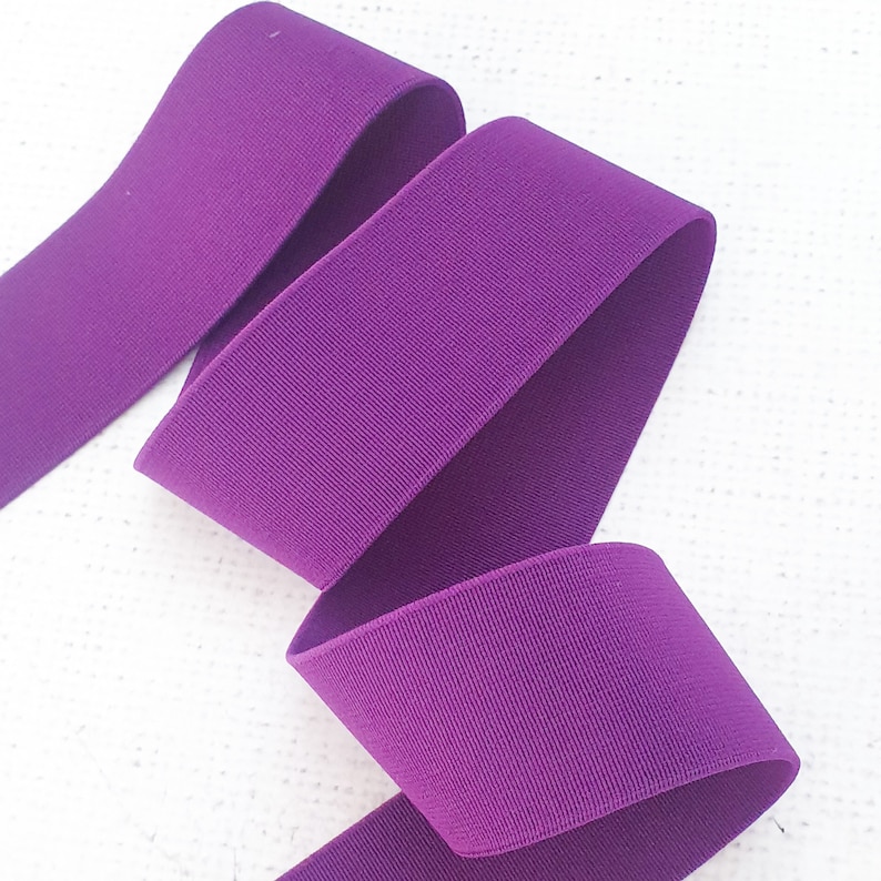 Pu&ograve; includere: Nastro elastico viola, piegato in tre parti, mostrando la trama e il colore del tessuto.