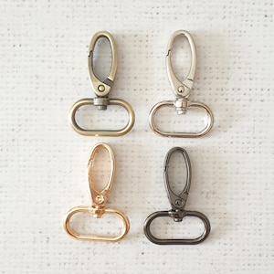 May include: Four metal swivel clasps in different finishes: gold, silver, brass, and black. Each clasp has a D-ring shape with a spring-loaded gate.