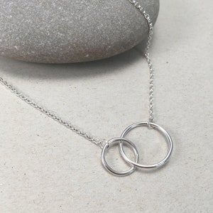 May include: A silver chain necklace with two interlocking circles as a pendant.