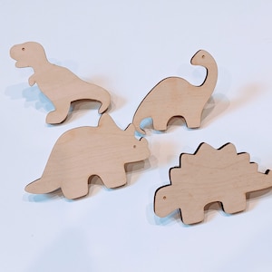 May include: Four wooden dinosaur shapes, including a stegosaurus, triceratops, brachiosaurus, and tyrannosaurus rex. The dinosaurs are unpainted and ready to be decorated.