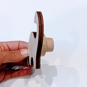 May include: A wooden dinosaur-shaped wall hook with a brown stain finish. The hook is designed to resemble a standing dinosaur with a curved neck and tail.