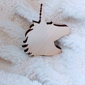 Peut inclure: Découpe en bois d'une tête de licorne avec une corne en spirale. La découpe est de couleur brun clair et a une finition lisse.