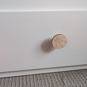 May include: A white drawer with a wooden basketball-shaped knob.