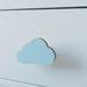 May include: A white chest of drawers with a light blue cloud-shaped handle. The handle is made of wood and has a simple design. The chest of drawers has a smooth, painted finish.