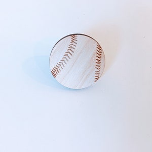 May include: White wooden baseball with brown stitching.