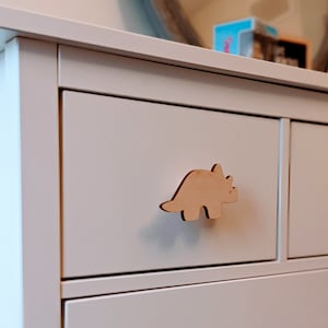 May include: White dresser with a wooden dinosaur-shaped drawer pull.
