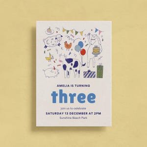 Puede incluir: Una tarjeta de invitación blanca con una ilustración caprichosa de animales de granja, globos y confeti. El texto dice "AMELIA IS TURNING THREE" con detalles de la fiesta. La tarjeta está sobre un fondo amarillo claro.