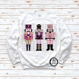 May include: White sweatshirt with three pink and black nutcracker figures with glitter accents. The text "DO NOT COPY" is repeated in black on the sweatshirt.