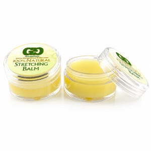 Puede incluir: Dos tarros pequeños, redondos y de plástico transparente que contienen un bálsamo amarillo pálido. Un tarro está cerrado con una tapa con un logotipo verde y el texto 100% NATURAL STRETCHING BALM. El segundo tarro está abierto, mostrando el bálsamo.