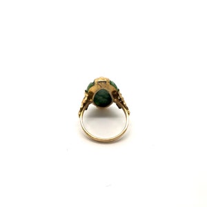 May include: A gold ring with a green gemstone set in a floral design.