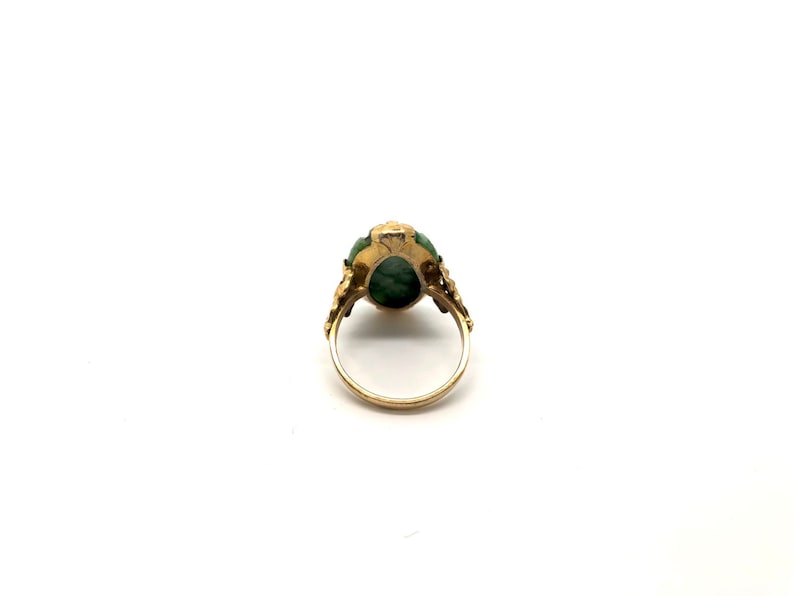 May include: A gold ring with a green gemstone set in a floral design.