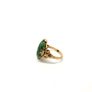 May include: A gold ring with a green jade stone set in a delicate filigree design.