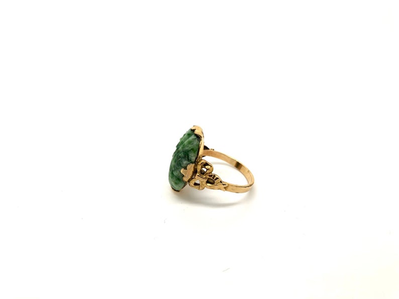 May include: A gold ring with a green jade stone set in a delicate filigree design.