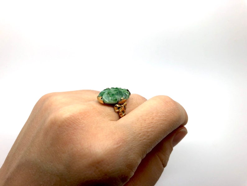 May include: A gold ring with a green jade stone. The stone is carved with a floral design.