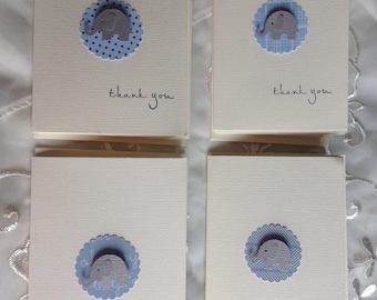 May include: Four ivory thank you cards with a blue elephant design. Each card features a gray elephant on a blue scalloped circle. The words "thank you" are written in cursive below the design.