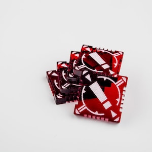 Op de afbeelding: Een stapel rode plastic spelstukken met een wit uitroepteken in het midden. Elk stuk heeft een getextureerde rand.