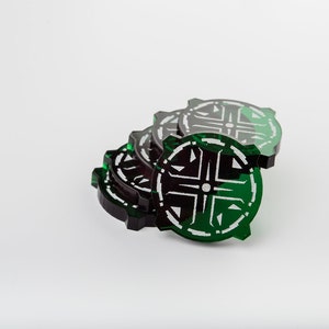 May include: A stack of green and black acrylic poker chips with a geometric design.