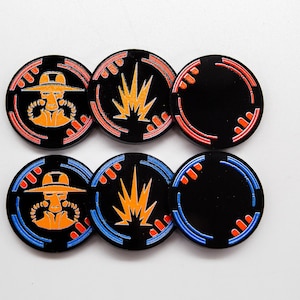 May include: Six black, round tokens with colorful designs. Two tokens feature an orange figure in a hat, two have an orange burst, and two are blank with a colored border. The borders are red and blue.