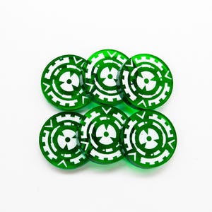Op de afbeelding: Zes groene, ronde spel fiches met een wit, gestileerd tandwiel ontwerp. De fiches zijn gerangschikt in twee rijen van drie tegen een witte achtergrond. Het ontwerp heeft een centrale cirkel en uitstralende lijnen.