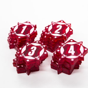 May include: Four stacks of red, star-shaped game pieces with white numbers 1, 2, 3, and 4. Each piece has a white starburst design around the number. The pieces are on a white background.