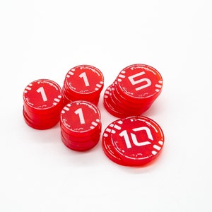 May include: A stack of red plastic game tokens with white numbers. The numbers are 1, 5, and 10.