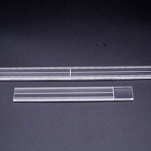 May include: Two clear plastic rulers with a graduated scale. The larger ruler is approximately 12 inches long and the smaller ruler is approximately 6 inches long.