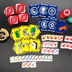 May include: A collection of board game components including red dice with white symbols, blue hexagonal tiles with various icons, yellow hexagonal tiles featuring illustrations of urban objects, small square tokens with diverse graphics, and two circular tokens.