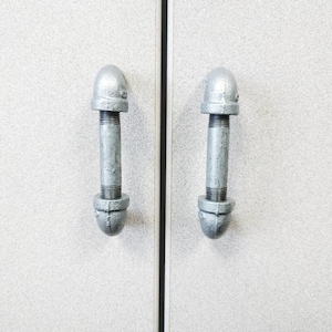 May include: Two silver metal cabinet door pulls with a rounded top and a threaded design.