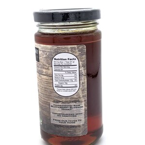 May include: A glass jar of raw blackberry blossom honey. The label reads "Ingredients: Raw Blackberry Blossom Honey" and "Unpasteurized with no additives". The label also says "From our hives to your home".