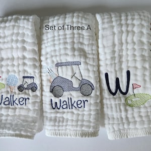 May include: Set of three white muslin burp cloths with embroidered golf-themed designs. One cloth features a golf cart and the name "Walker", another features a golf cart and the name "Walker", and the third features a large "W" and a golf flag.