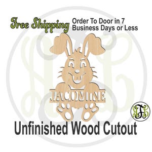 May include: Unfinished wooden cutout of a bunny rabbit with the name "JACOMINE" written on a banner held by the bunny. The bunny is smiling and has large ears.