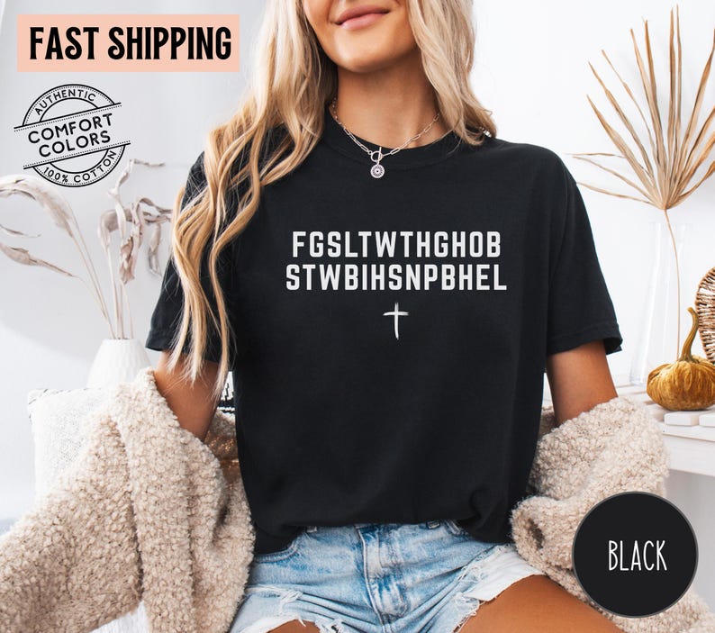 Puede incluir: Camiseta negra con texto blanco y una cruz. El texto dice "FGSLTWTHGHOB STWBIHSNPBHEL". La camiseta es 100% algod&oacute;n y presenta una pancarta de "Env&iacute;o r&aacute;pido".