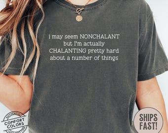 Puede incluir: Camiseta gris oscuro con el texto blanco: "i may seem NONCHALANT but I'm actually CHALANTING pretty hard about a number of things". La camiseta tiene un aspecto vintage y una etiqueta Comfort Colors.
