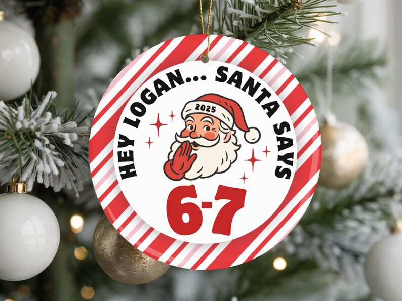 May include: Round Christmas ornament with a red and white striped border. The ornament features the text "HEY LOGAN... SANTA SAYS" around a Santa Claus graphic. The numbers "6-7" are in red below Santa.