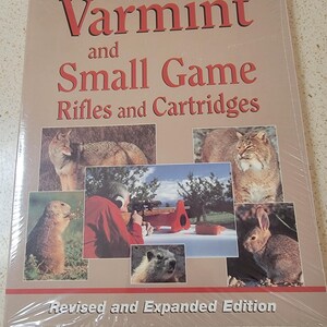 May include: A book titled "Varmint and Small Game Rifles and Cartridges" with a revised and expanded edition label. The cover features photos of various animals, including a fox, a bobcat, a prairie dog, a marmot, and a rabbit.