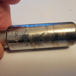 May include: A silver metal socket wrench with the text "MAC" and "SABINA" on the side.