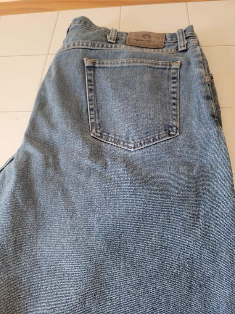 Puede incluir: Vaqueros de mezclilla azul claro con un dise&ntilde;o cl&aacute;sico de cinco bolsillos. Los vaqueros tienen un bolsillo trasero y un parche de cuero con el logotipo de la marca. La mezclilla tiene un aspecto descolorido, lo que sugiere desgaste y lavado.